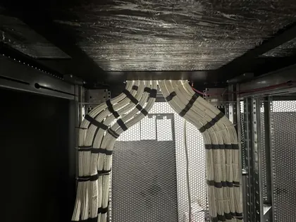 Structured cabling entering a rack in two symmetrical sweeping bundles, each run combed flat and secured at regular intervals with hook-and-loop ties